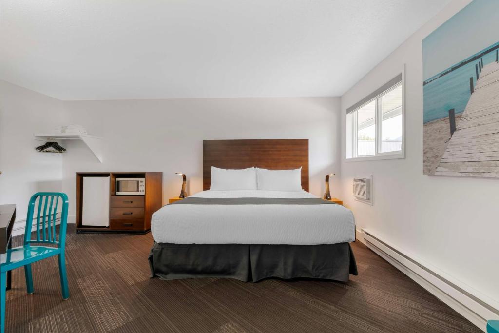 a bedroom with a large bed and a blue chair at Stoke Hotel SureStay Collection by Best Western in Revelstoke