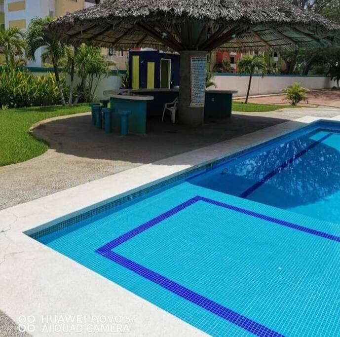 a blue swimming pool with a table and a building at Departamento ACAPULCO PROMOCIÓN in Aguacatillo