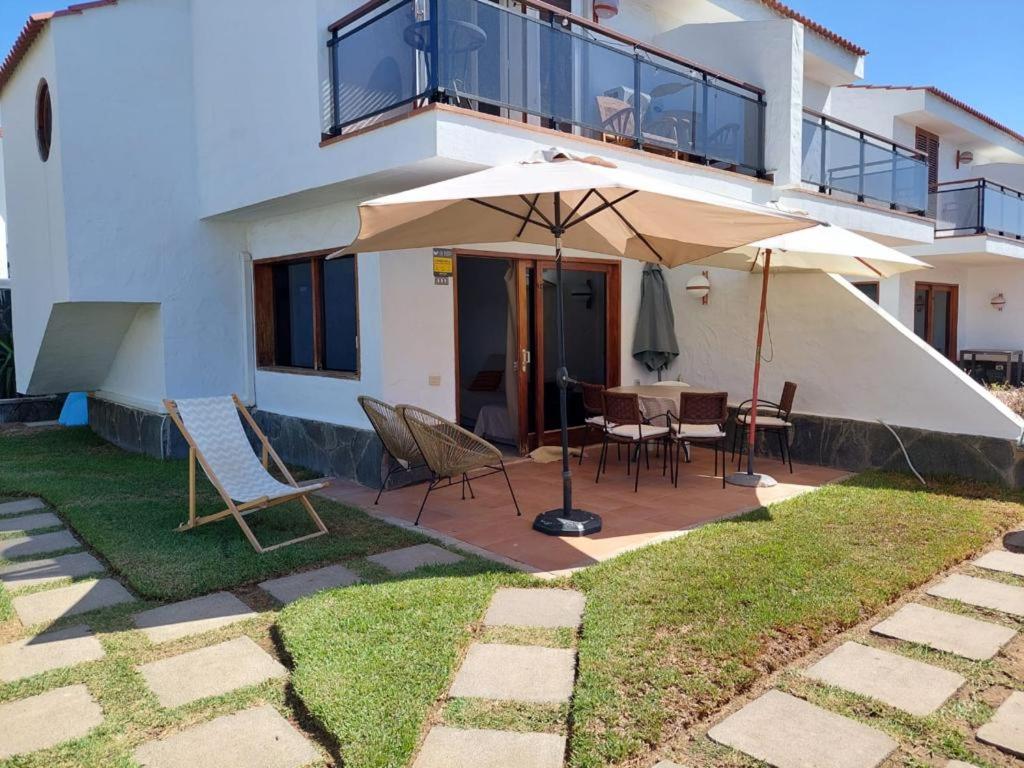 una casa con patio con tavolo e ombrellone di La casa de la playa San Agustín a Maspalomas