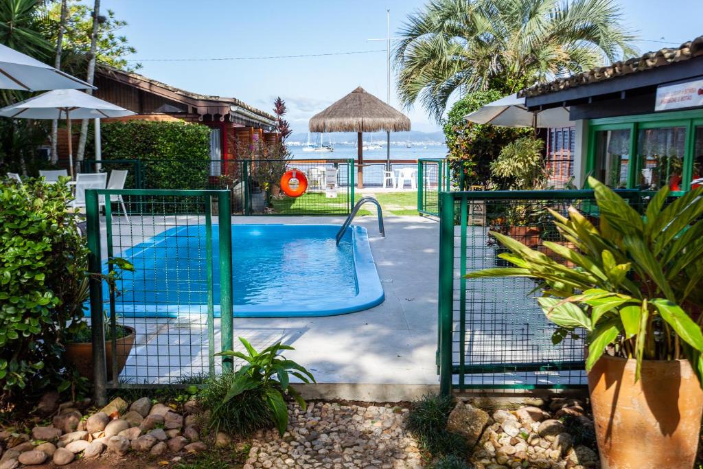 a swimming pool in a yard with an open gate at Pousada Mar de Dentro in Florianópolis