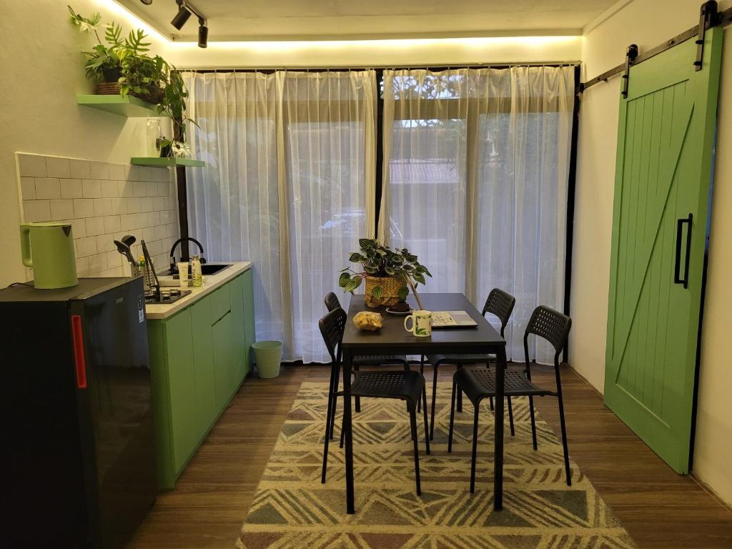 een tafel en stoelen in een keuken met groene kasten bij Tepas Paviliun in Bandung
