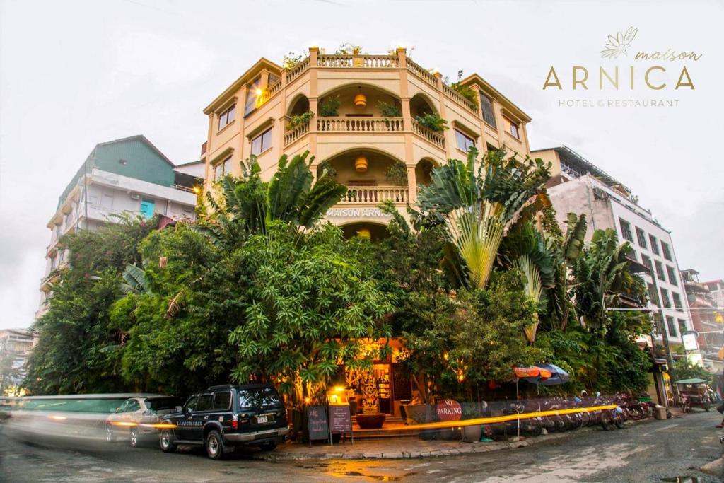 een groot gebouw aan de kant van een straat met bomen bij Maison Arnica Hotel & Restaurant in Phnom Penh