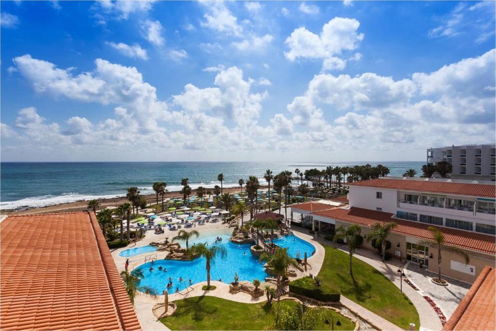 an aerial view of a resort with a pool and the ocean at Leonardo Cypria Bay in Paphos