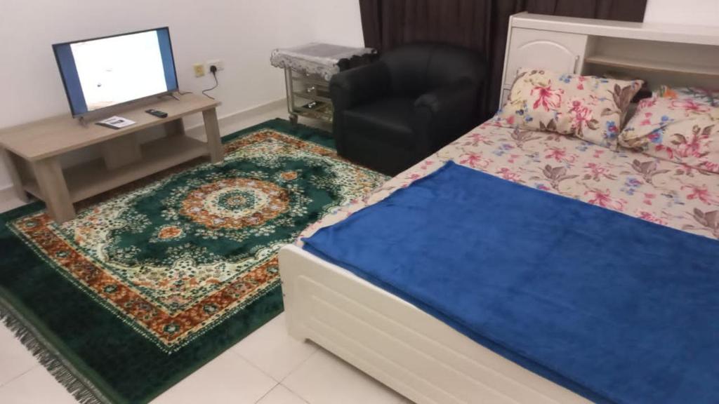 a bedroom with a bed and a desk and a television at Budget Place in Dubai