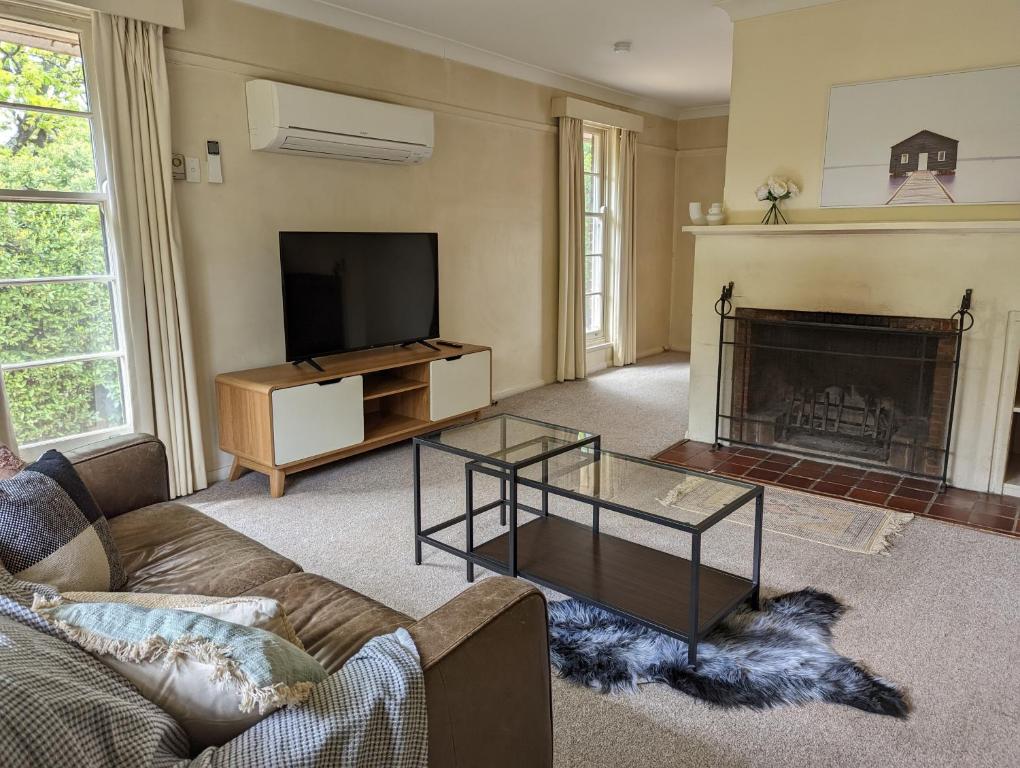 a living room with a couch and a tv and a fireplace at A Classic Deakin Delight in Yarralumla