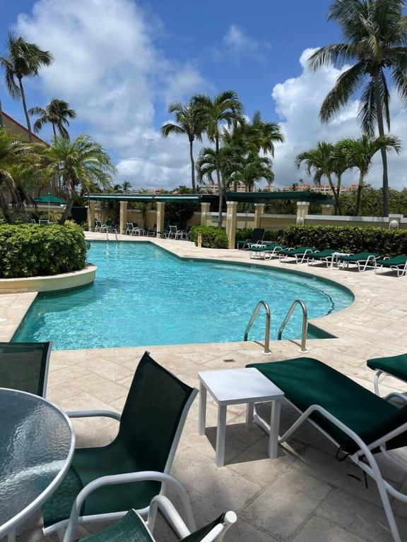a swimming pool with chairs and a table in a resort at Carey Beach Villa in Humacao