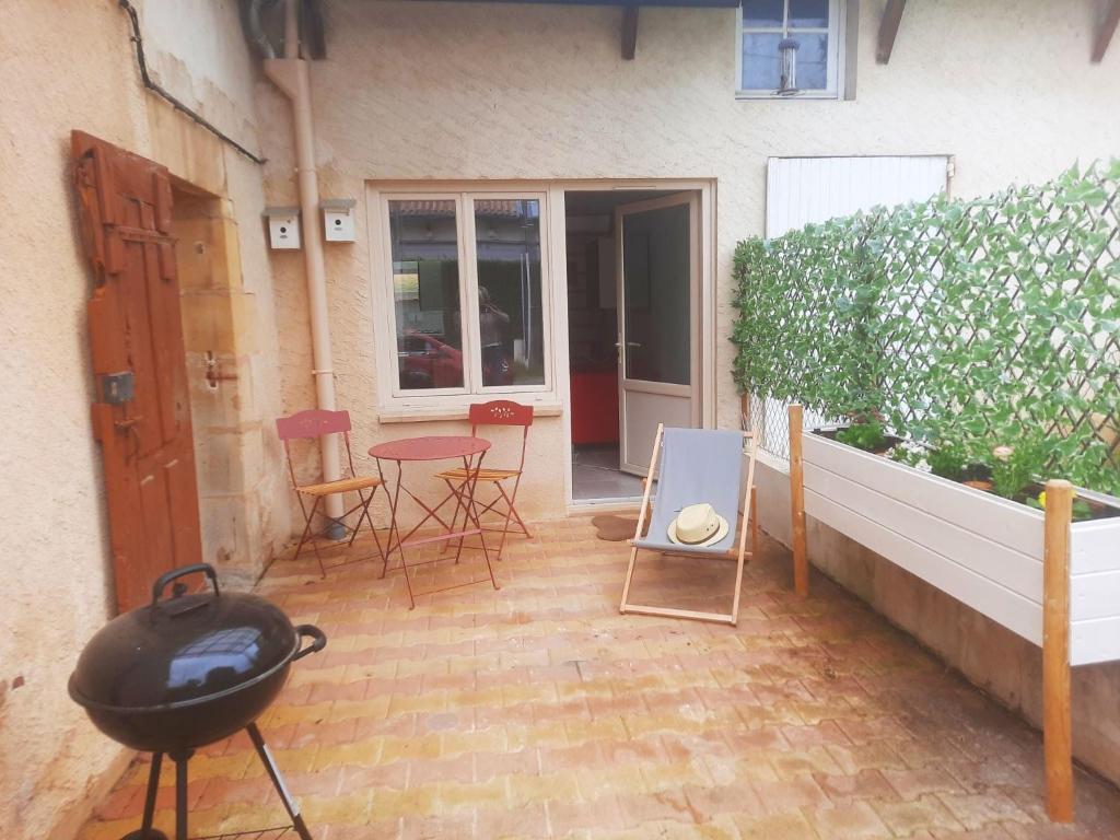 um pátio com comodidades para churrascos e cadeiras e um edifício em Snug holiday home in Bergerac with terrace em Bergerac