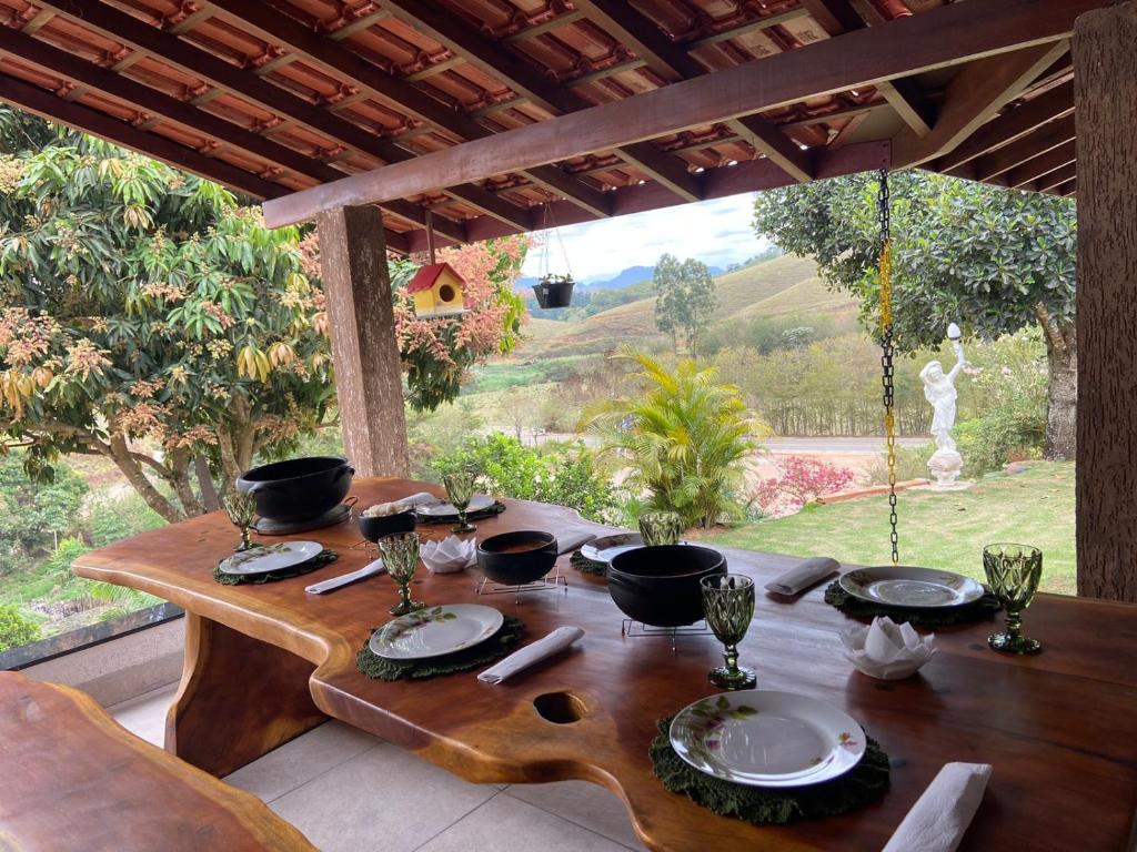 - une table en bois avec des assiettes et des ustensiles de cuisine sur la terrasse dans l'établissement Pousada Recanto Querubim, à Siqueira Campos