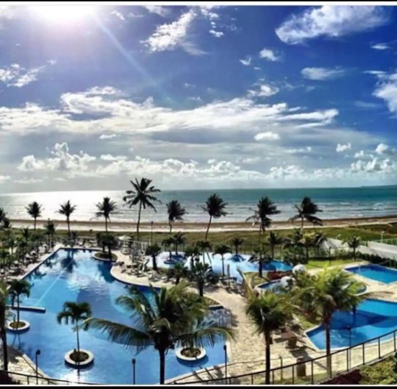 uma vista para um resort com palmeiras e a praia em Apartamento a beira-mar com piscina em Cabedelo