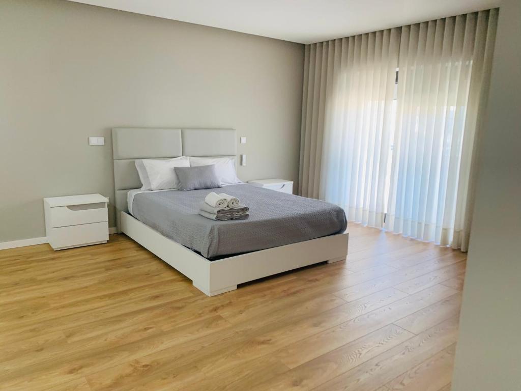 um quarto branco com uma cama e piso em madeira em RealGoios em Esposende