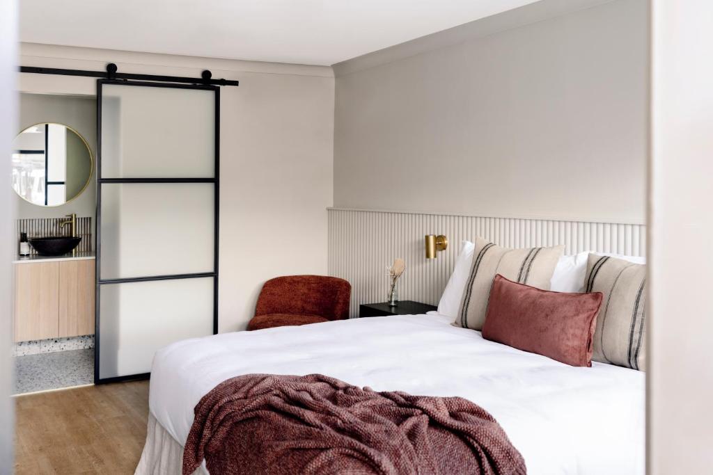 Motel Caloundra في كالوندرا: غرفة نوم بسرير ابيض وكرسي احمر