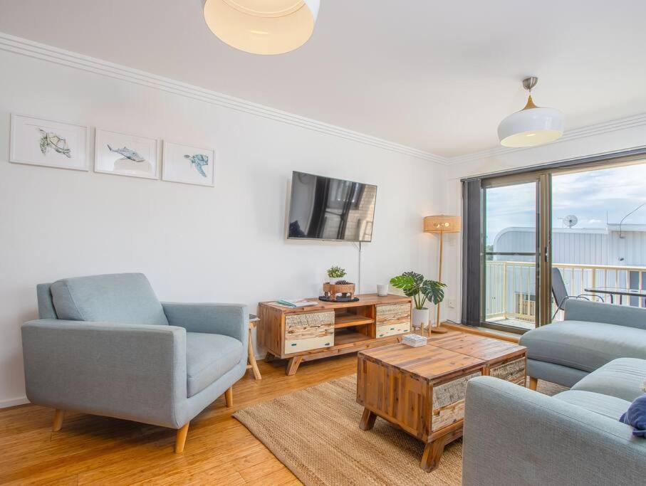 a living room with two blue chairs and a tv at Kingscliff Beachfront Abode - Hosted by Holiday Management in Kingscliff