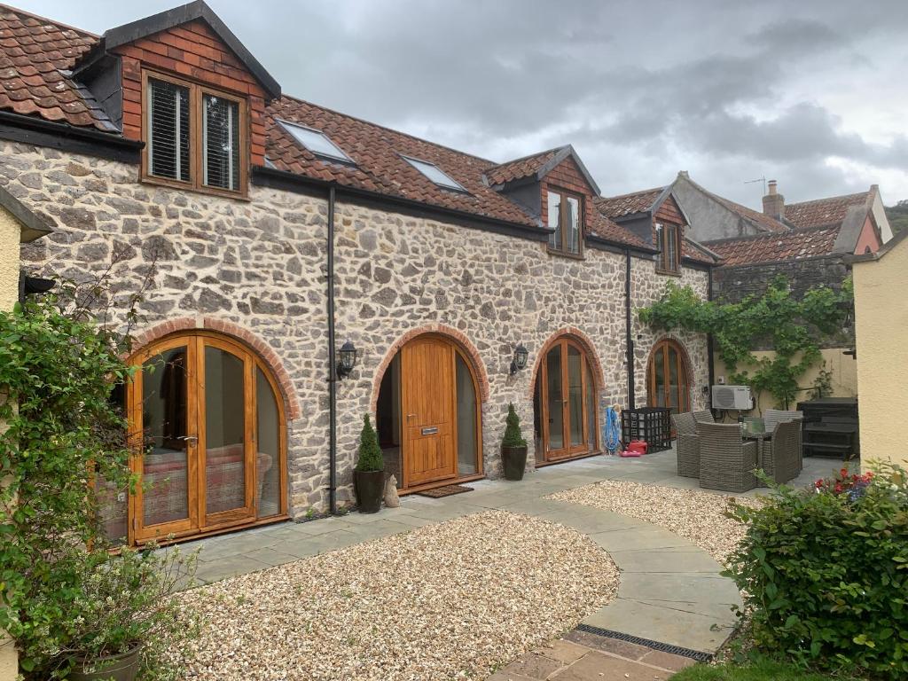 a stone house with wooden doors and a patio at Sutherland Barn in Weston-super-Mare