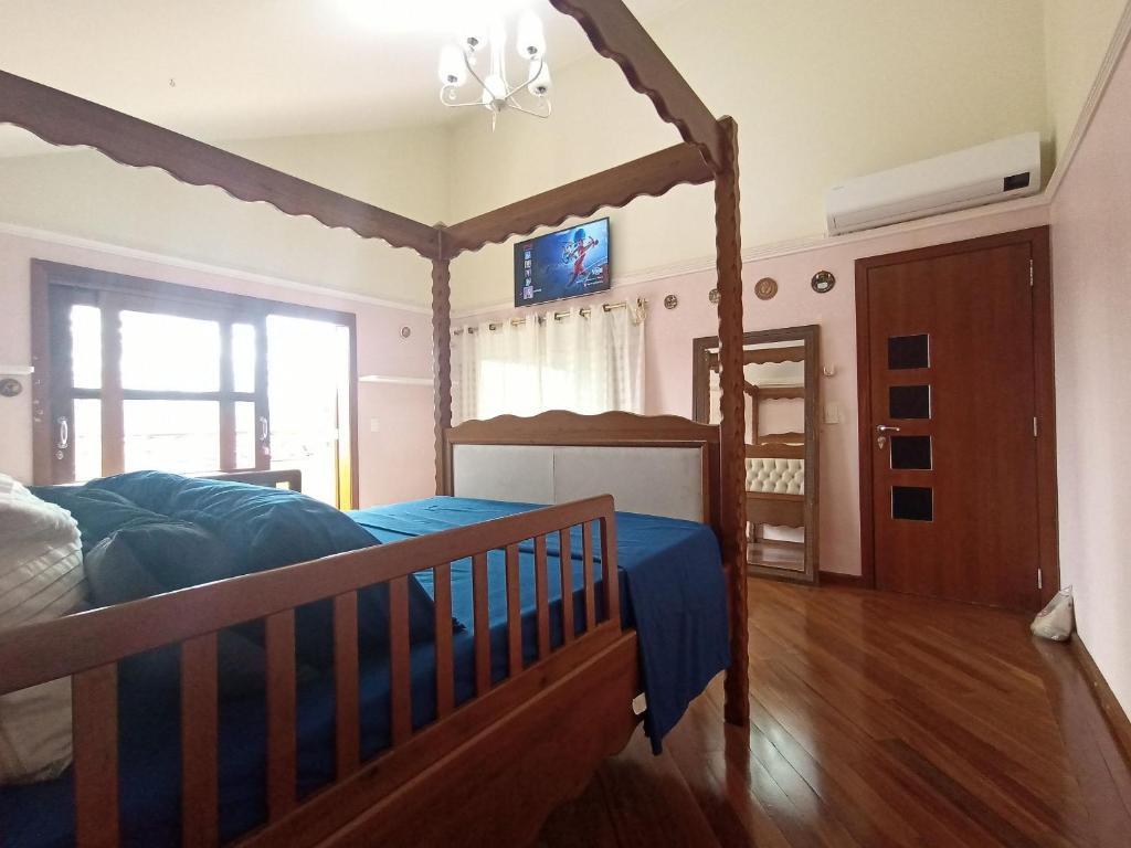 ein Schlafzimmer mit einem Bett mit einem Bettrahmen aus Holz in der Unterkunft Casa Central Art Decor com Piscina e BBQ in Foz do Iguaçu