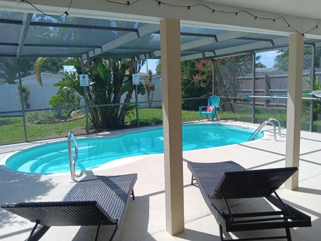 un patio con 2 sillas y una piscina en Private & Screened in Pool en Port Richey