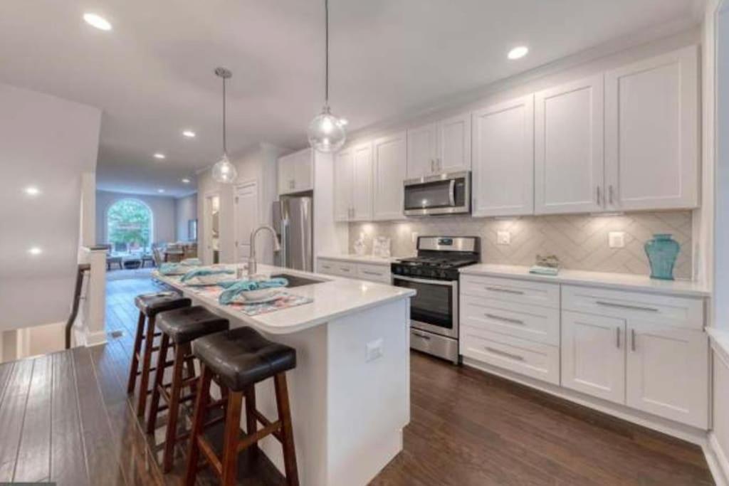 a kitchen with white cabinets and a kitchen island with bar stools at Beautiful Canton Home w/rooftop deck +Private parking in Baltimore