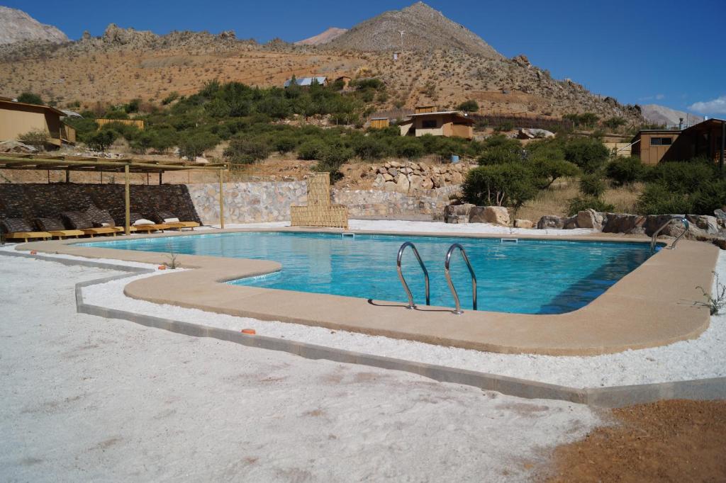 a swimming pool with a mountain in the background at Samay Lodge in Cochiguaz