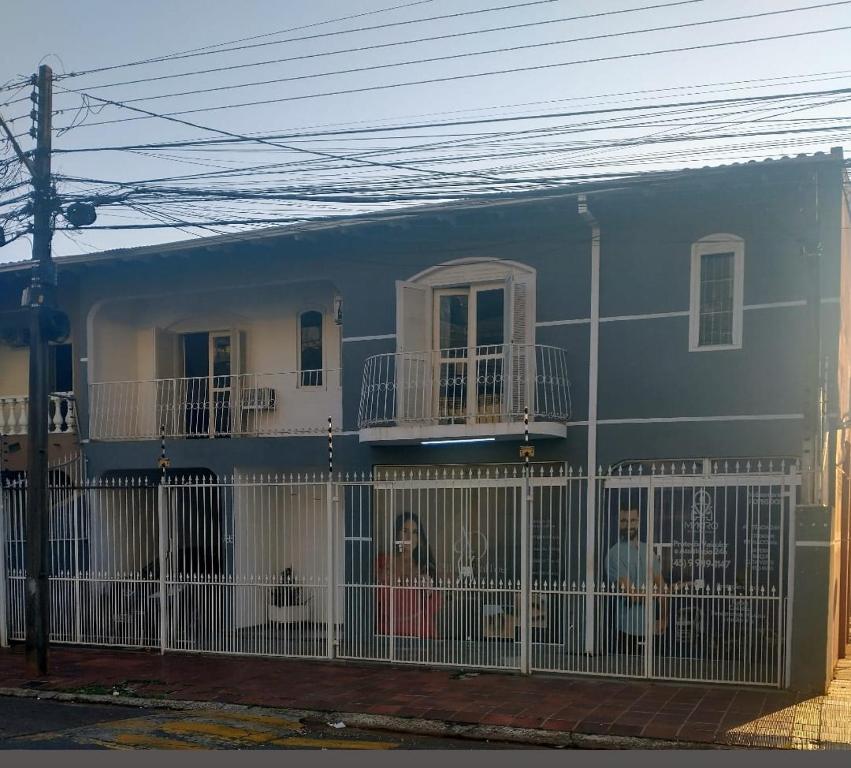 una casa azul con una valla blanca delante de ella en Casa Centro de Foz do Iguaçu com piscina e churrasqueira, en Foz do Iguaçu
