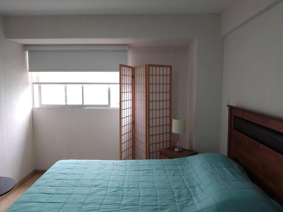 利馬的住宿－Hermoso departamento céntrico con balcón - P.Libre，一间卧室设有一张绿色的床和一个窗户。