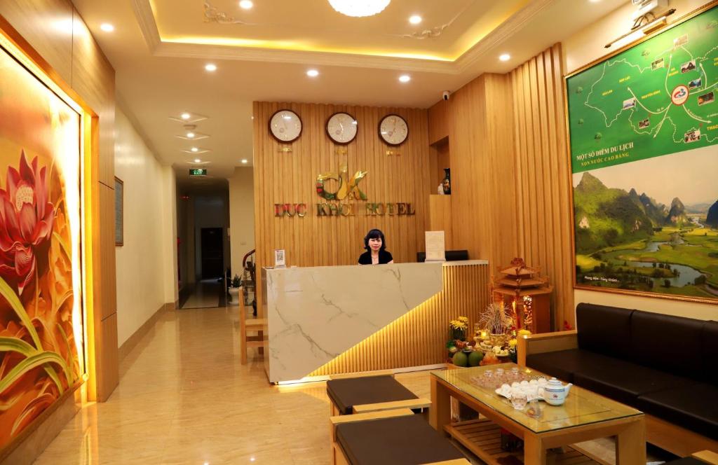 a woman standing behind a counter in a room with clocks at Đức Khôi Hotel in Cao Bằng