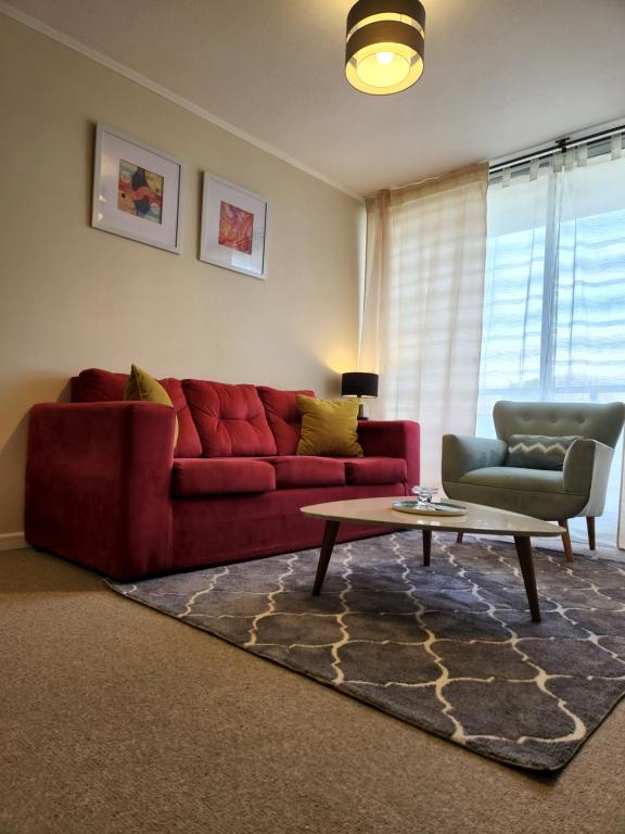 Sala de estar con sofá rojo y mesa de centro en Condominio privado. Cómodo y central departamento nuevo en Talca