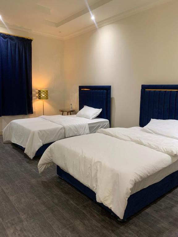 2 camas en una habitación con cortinas azules y mesa en شقة فاخرة في حطين en Riad