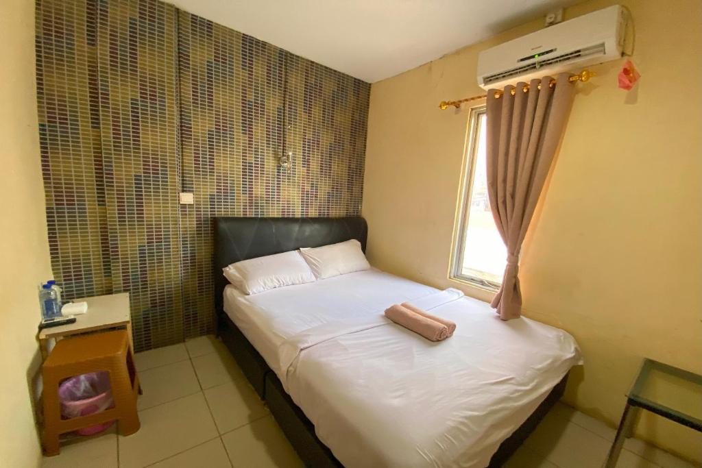 a small bedroom with a bed and a window at OYO 92932 Guesthouse Marbella in Nongsa
