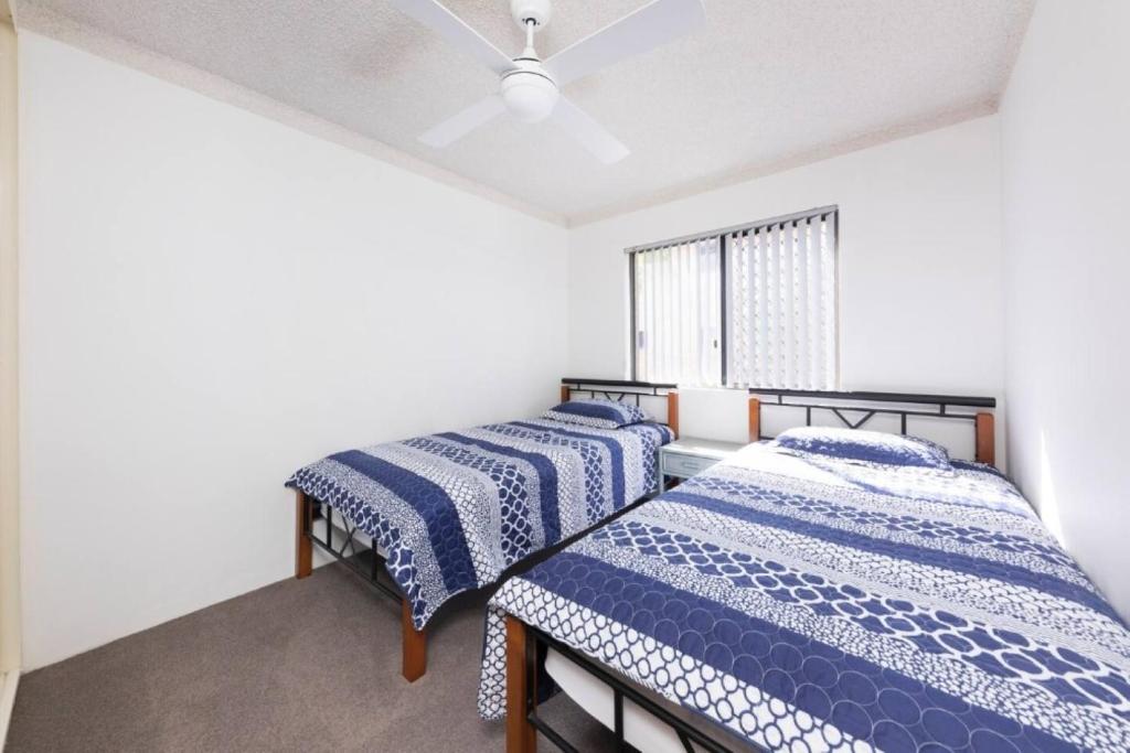 two beds in a room with white walls and a window at Breakers 3 - linen not included in Forster