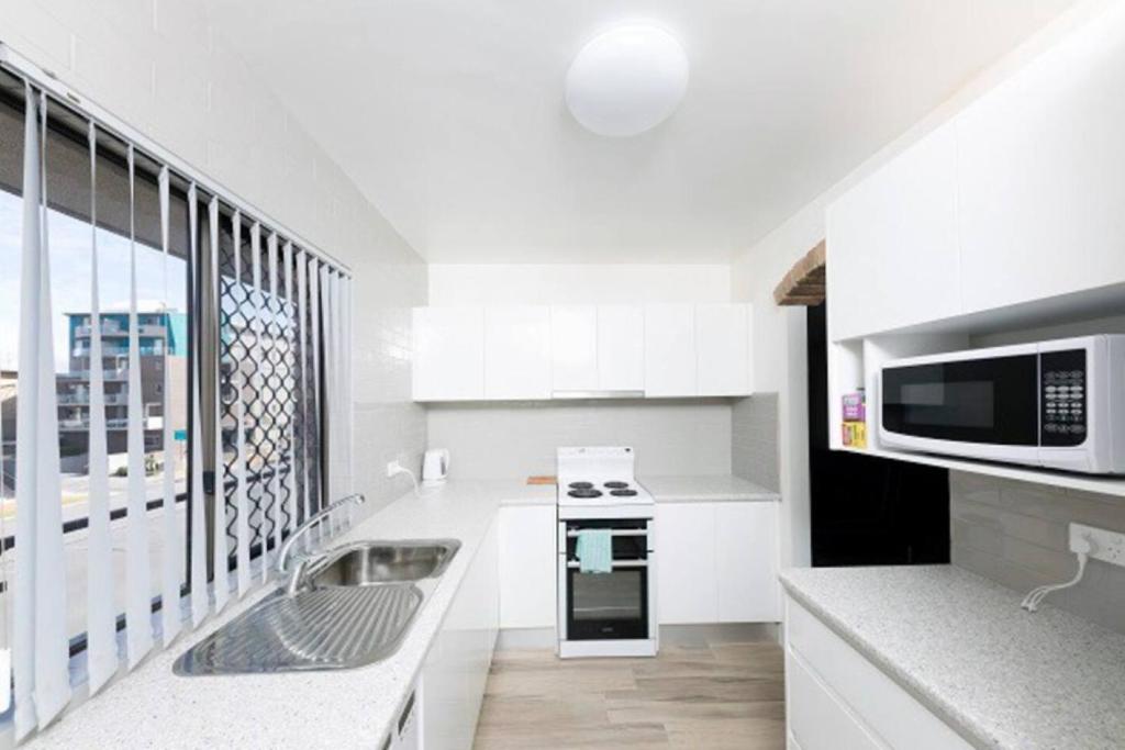 a white kitchen with a stove and a microwave at Breakers 3 - linen not included in Forster