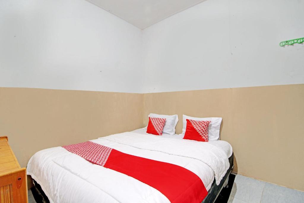 プカンバルにあるOYO 92933 Marvel House Syariahのベッドルーム1室(赤と白の枕が備わるベッド1台付)