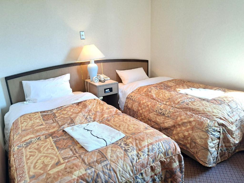 a hotel room with two beds and a lamp at Tetora Higashimuroran in Muroran