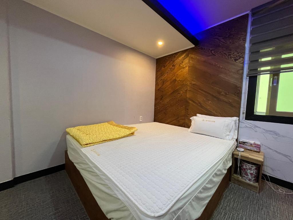 a bedroom with a bed with a yellow blanket on it at Maldives Hotel & Hostel in Busan