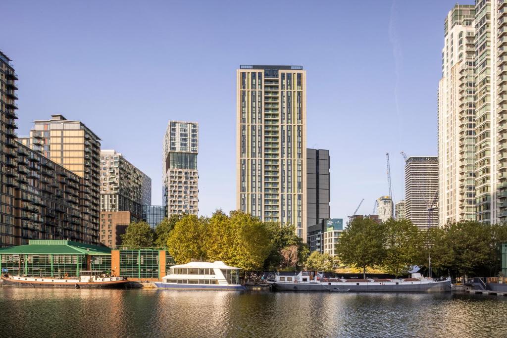a city with tall buildings and a river with boats at Urban Rest Canary Wharf Apartments in London