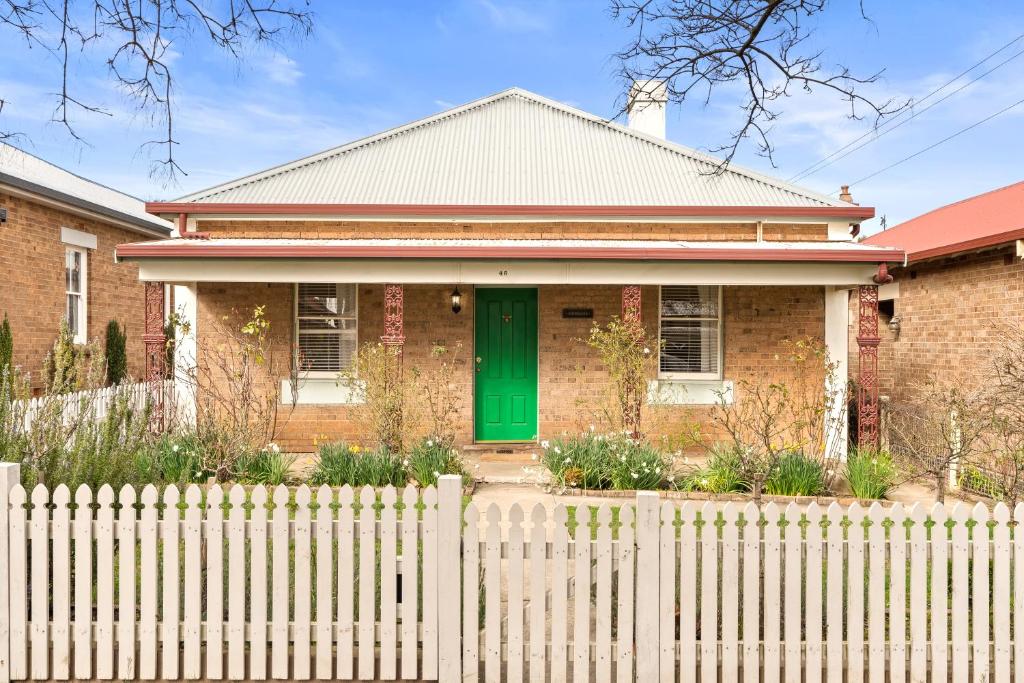 a brick house with a green door behind a fence at Ambrose On Byng - Central Location in Orange