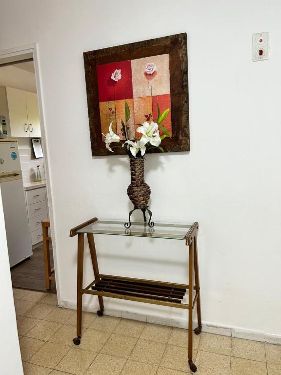 uma mesa de vidro com um vaso com flores em 3-х комнатная квартира у моря в Хайфе em Haifa