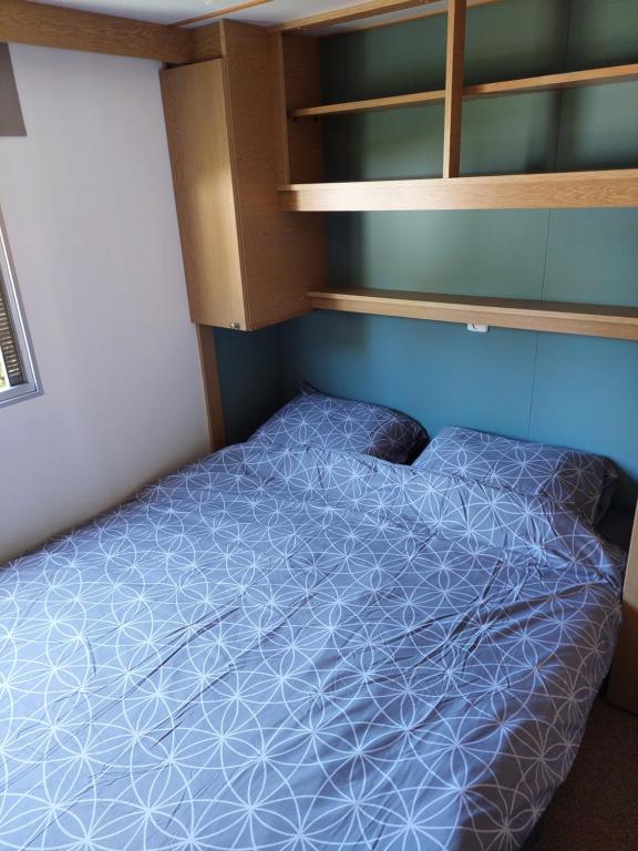 um pequeno quarto com uma cama com um edredão azul em Stelle Maris, Nice place WIFI and privacy em heinkenszand