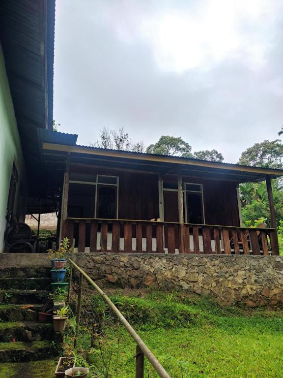 ein Haus mit einer Veranda und einer Steinmauer in der Unterkunft Lawi Luja Guest House in Kelimutu