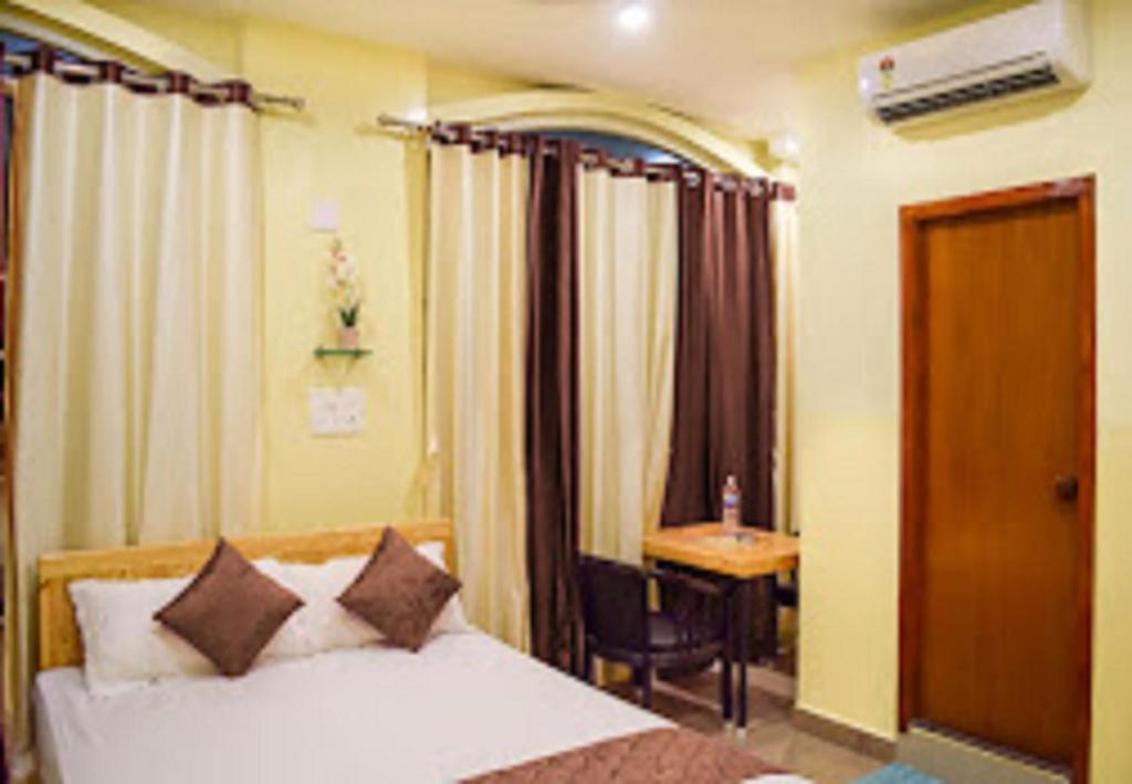 a bedroom with a bed and a table and a desk at Chaplin Hotel in Puducherry