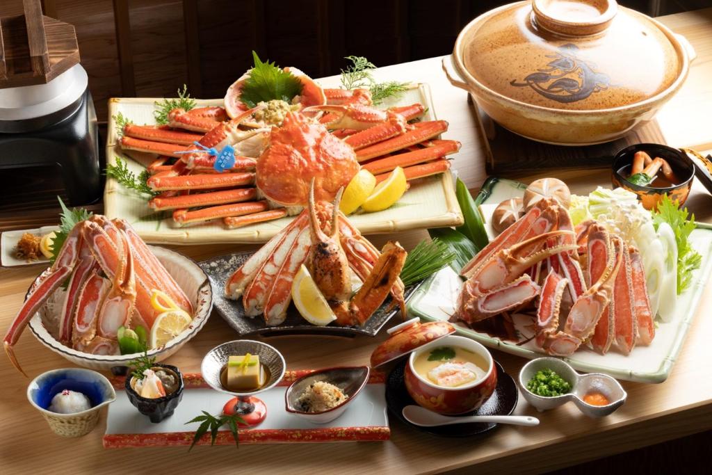 uma mesa com vários tipos diferentes de alimentos em 一日一組の隠れ宿　てらかわ em Kinosaki