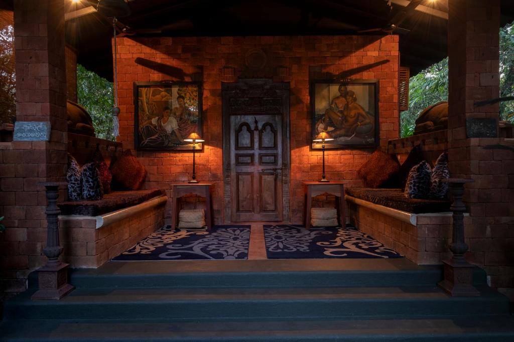 a house entrance with a wooden door and two benches at Casa Heliconia in Gampaha