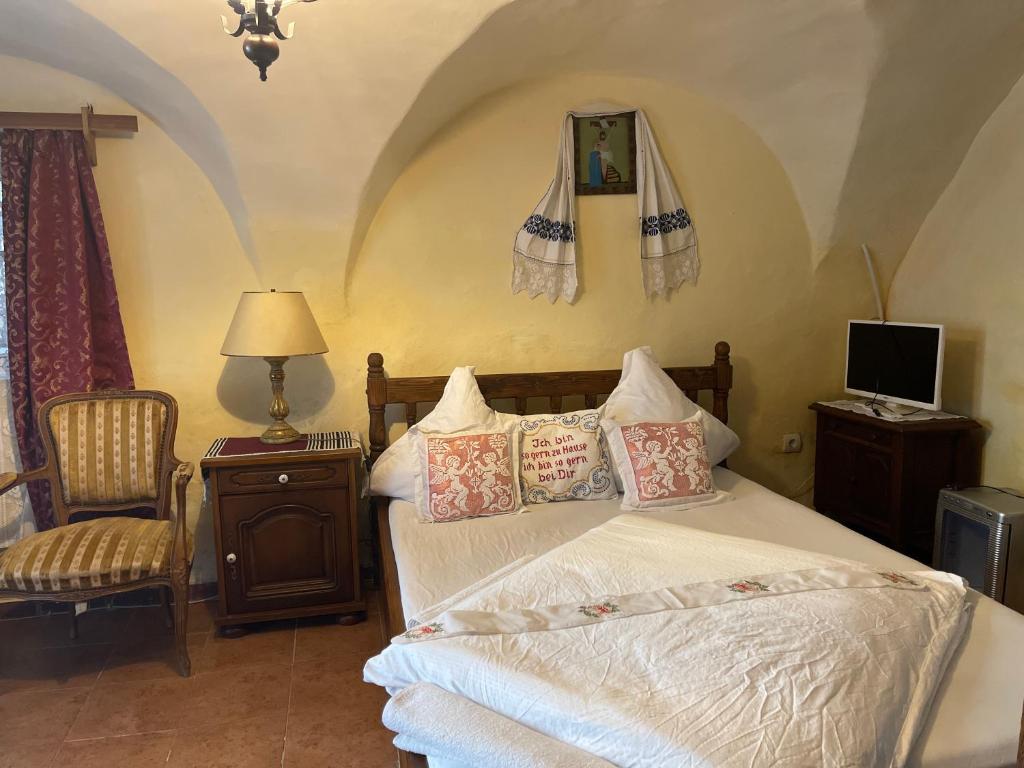 een slaapkamer met een bed, een stoel en een televisie bij Casa Morar in Sighişoara