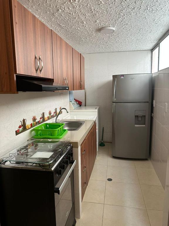 a kitchen with a stove and a stainless steel refrigerator at Apartamento cómodo con excelente ubicación in Bucaramanga