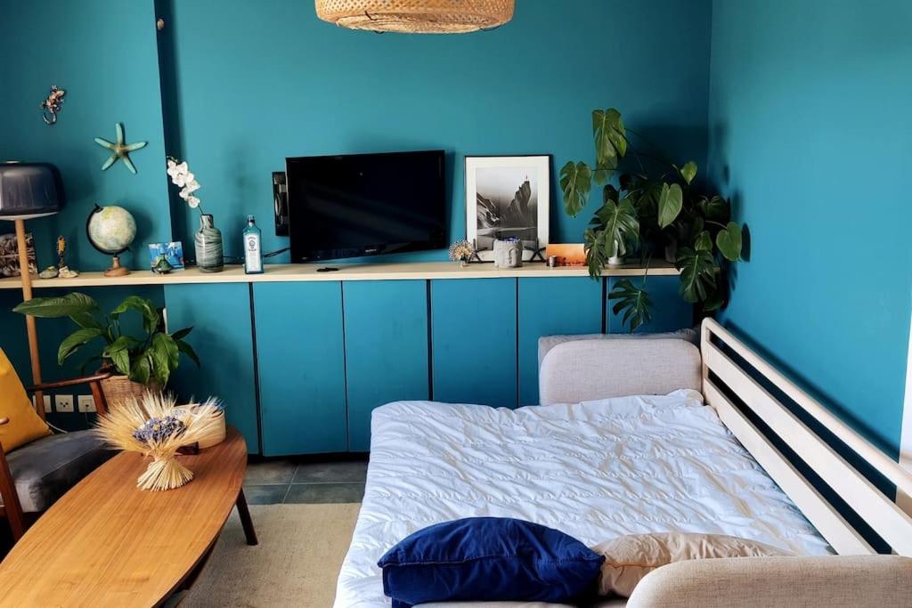 Habitación con pared azul, cama y mesa. en Charmant appartement avec magnifique vue, en Monnetier-Mornex