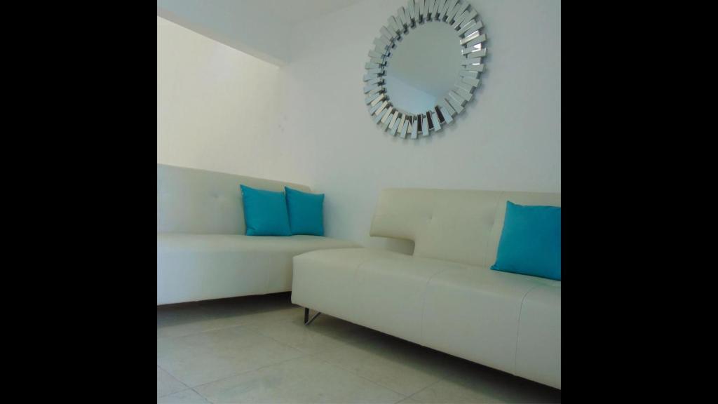 Sofá blanco con almohadas azules y espejo en Departamentos Villas Capdeviel, en Cancún