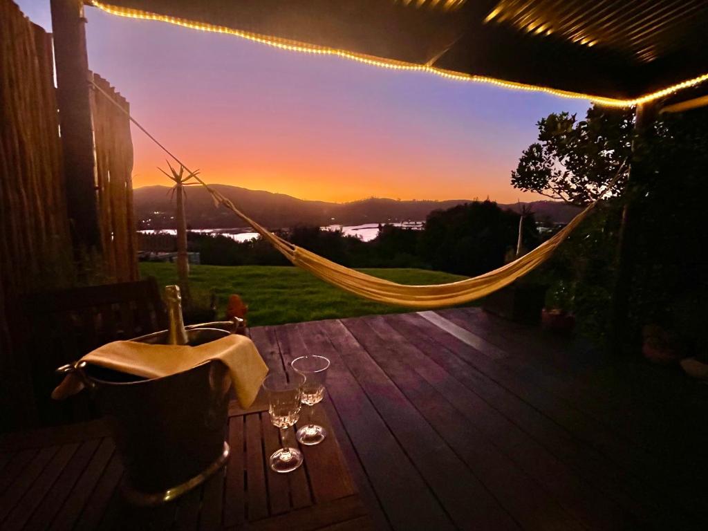 a hammock on a deck with a sunset in the background at Moonriver Cottage, Prime Lagoon Views & Solar Power in Knysna