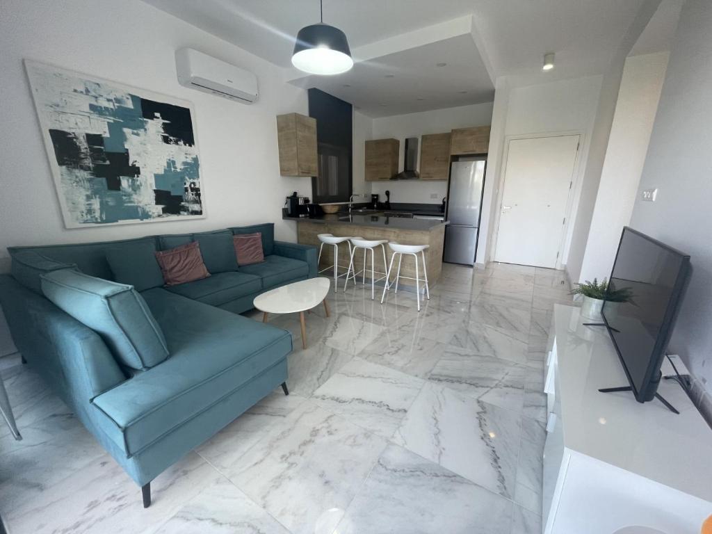 een woonkamer met een blauwe bank en een keuken bij Pafia 2, Apartment 202 in Paphos City