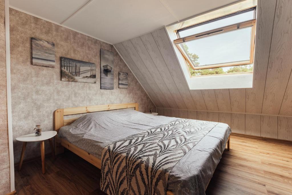 een slaapkamer met een bed en een raam bij Beach Home for Nature Lovers in Bernāti