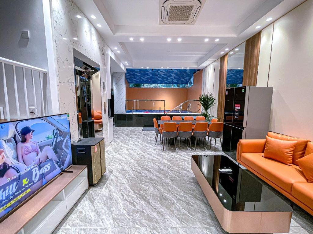 a waiting room with orange chairs and a flat screen tv at Happy Villa Hạ Long in Ha Long