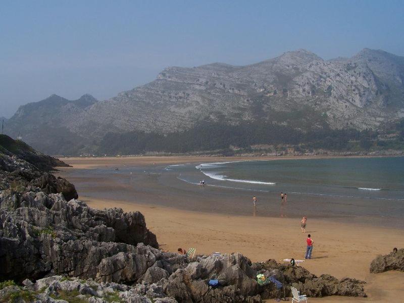 un grupo de personas en una playa con montañas en el fondo en La playa en Oriñón