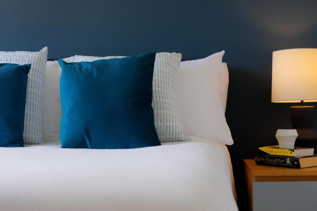 a bed with blue and white pillows and a table with a lamp at Amroth House in Cardiff